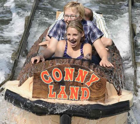 Ein Mädchen und eine Frau fahren sitzend in einem Baumstamm die Wildwasserbahn im Conny-Land